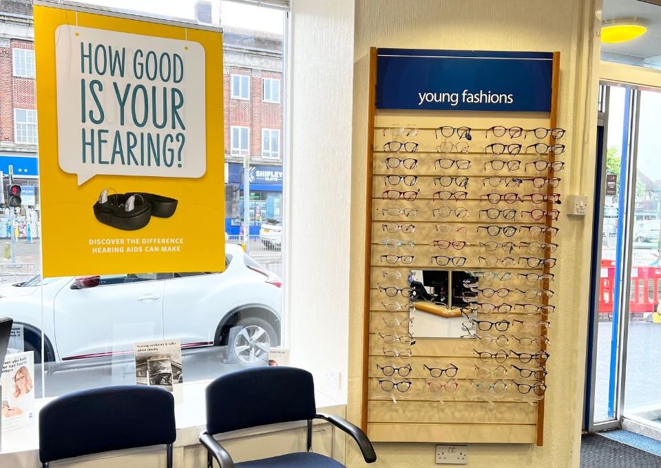 Bright yellow poster asks 'How good is your hearing?' with a picture of hearing aids underneath.