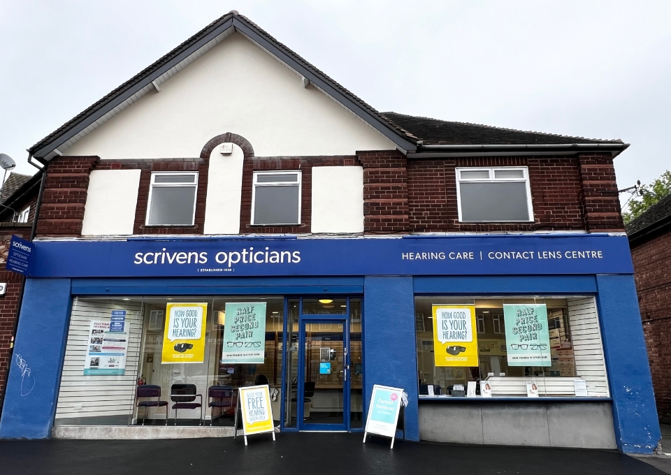 Blue storefront of Scrivens Opticians with hearing care and contact lens centre signage and posters in the windows