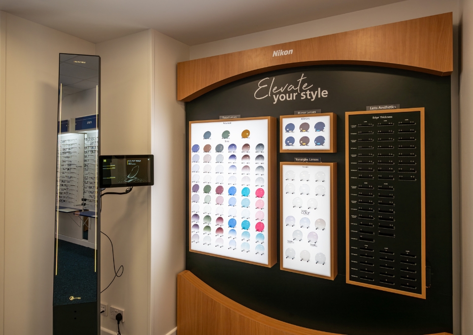 Eyewear lens display panels on a curved black wall with wooden frames and the slogan 'Elevate your style' above them in a store showroom.