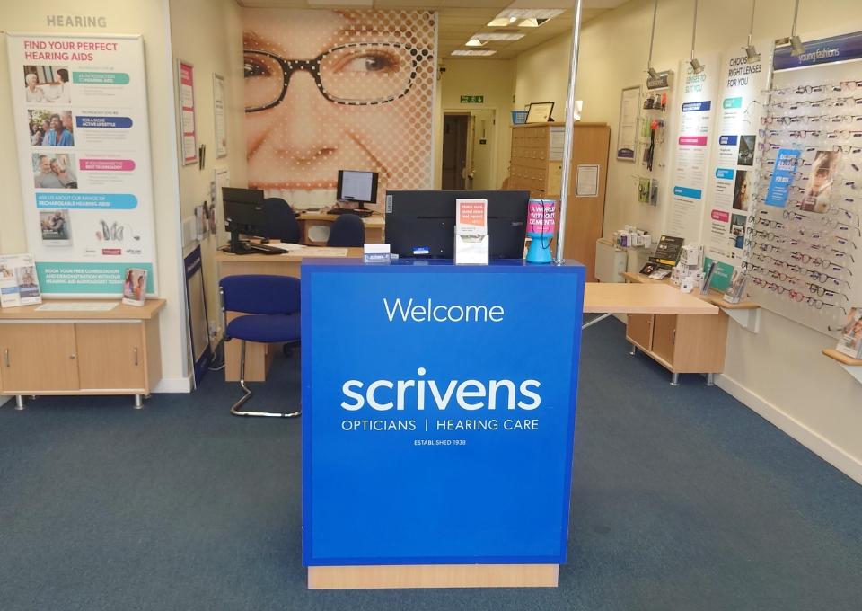 Reception desk at Scrivens Opticians and Hearing Care with a blue front displaying 'Welcome'