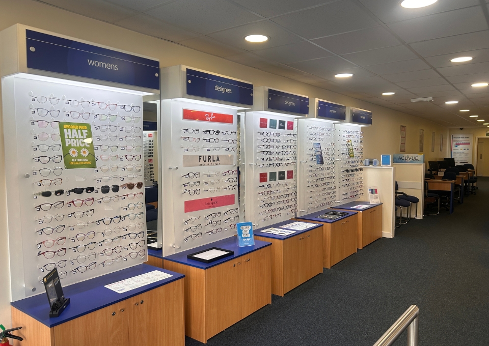Row of eyeglass display panels labeled 'women's' and 'designers' in an eyewear store. (Informative)