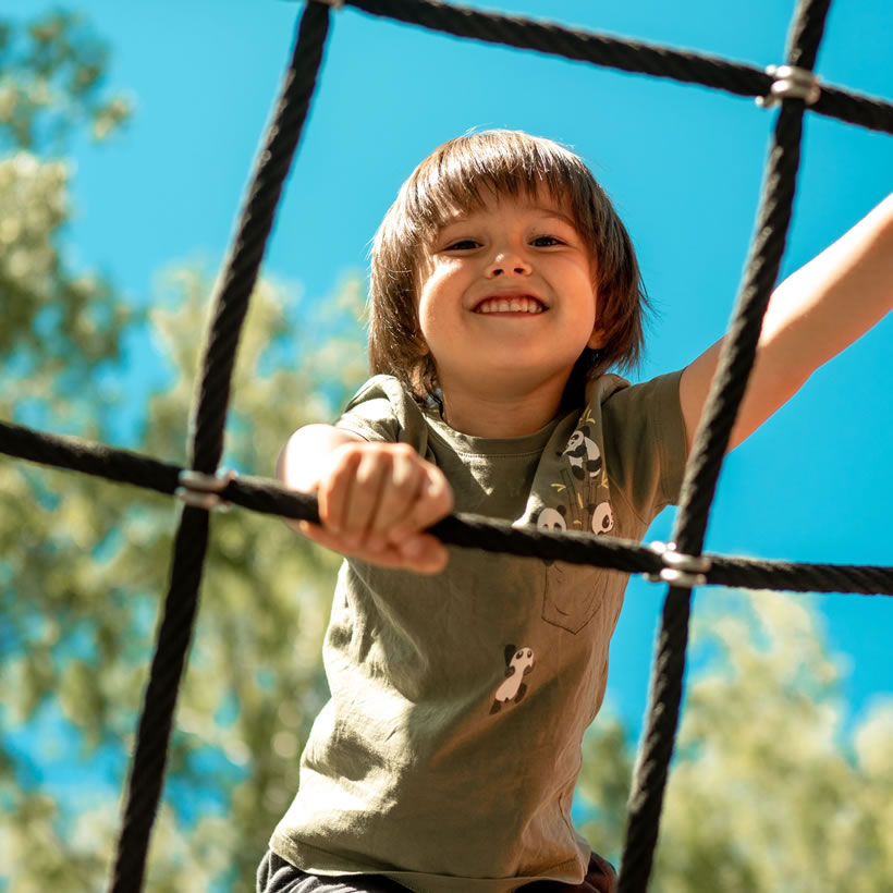 Small boy smiling on a climbing frame