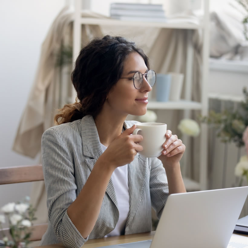 Young woman sat at a laptop drinking coffee in an art studio