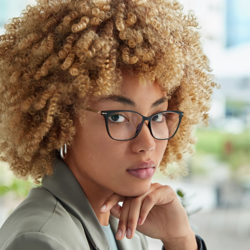 Lady with blond curly afro looking at the camera on a sunny day