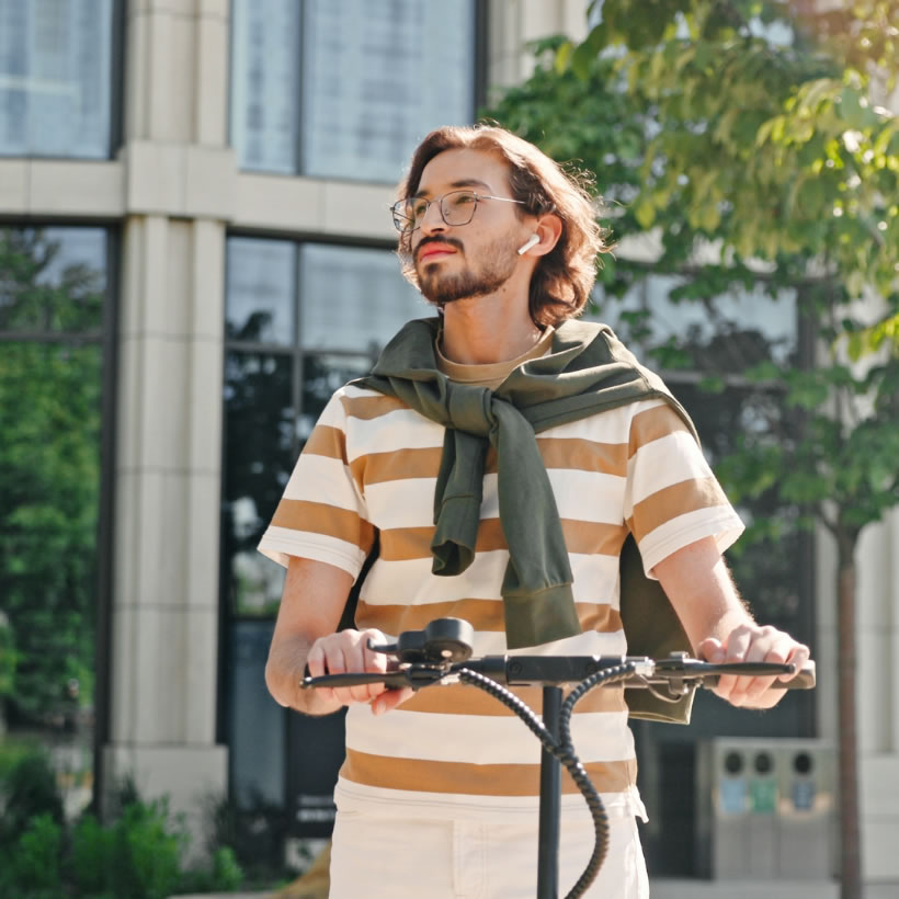 Happy man in striped t-shirt on a sunny day riding a scooter