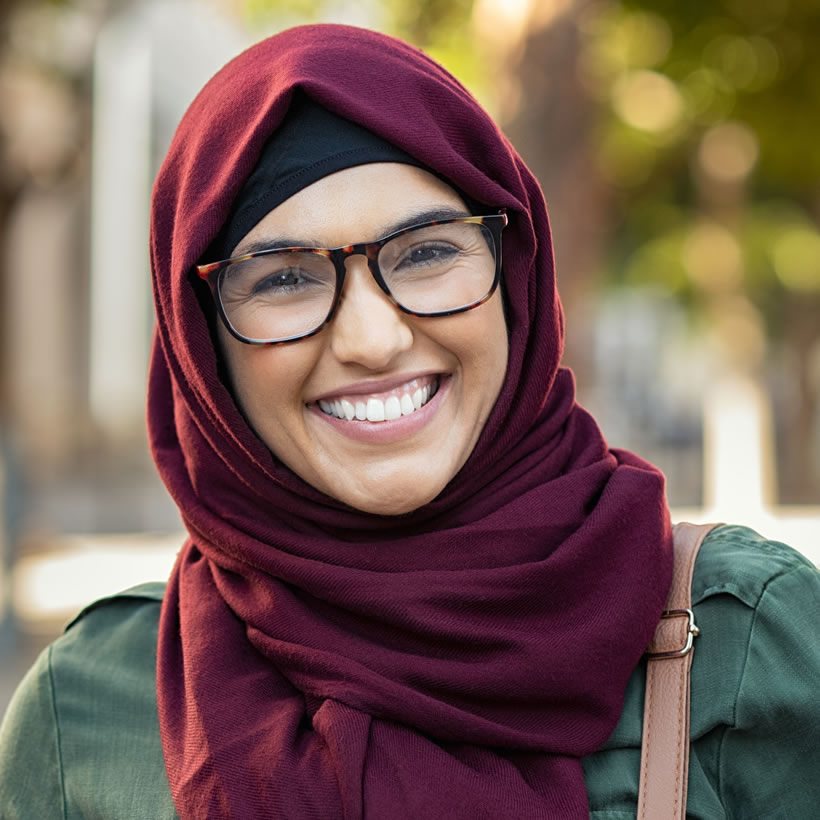 Young lady in headscarf wearing glasses with a big smile
