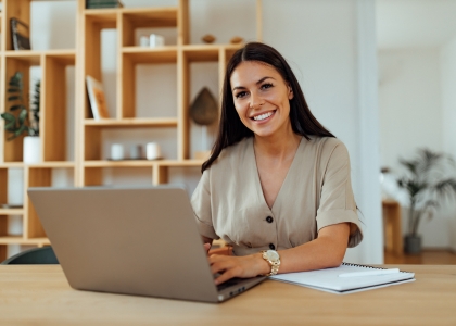 Woman sat at table smiling with laptop