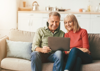 Middle aged man and woman sat on sofa with laptop
