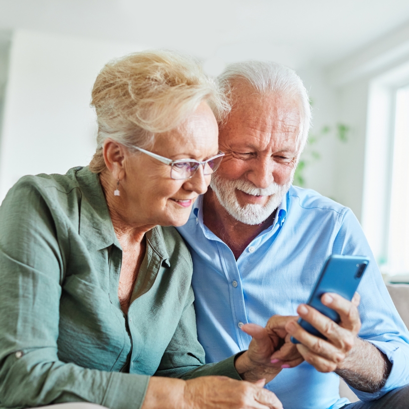 Older couple sat together looking at a phone