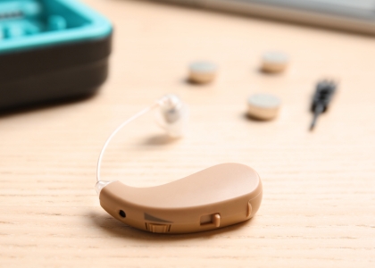 Hearing aid on table with hearing aid batteries in the background
