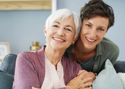 Elderly woman and younger woman holding hands on sofa