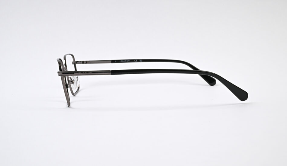 Side view of metal-framed eyeglasses with black temples on a white background, showing nose pads and thin rims.