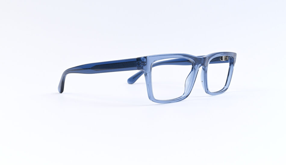 Blue transparent eyeglass frame lying on a white surface, viewed from the side.