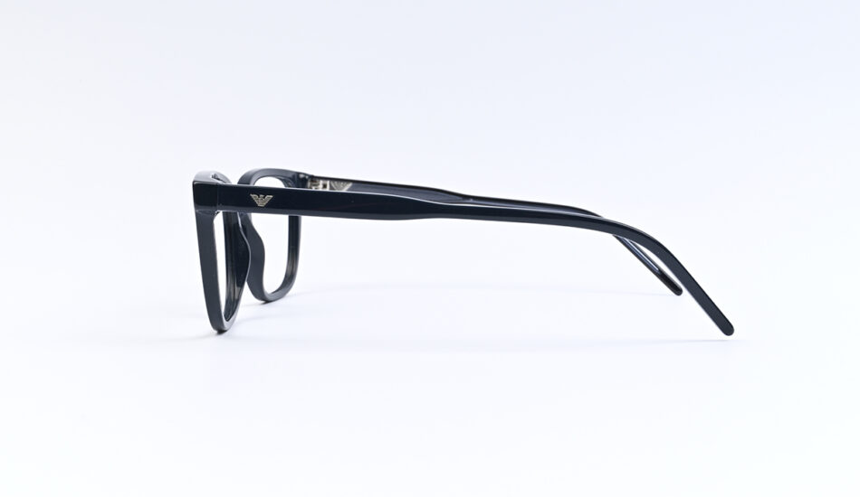 Black rectangular eyeglasses photographed from the side on a white background, with a subtle brand emblem on the temple.