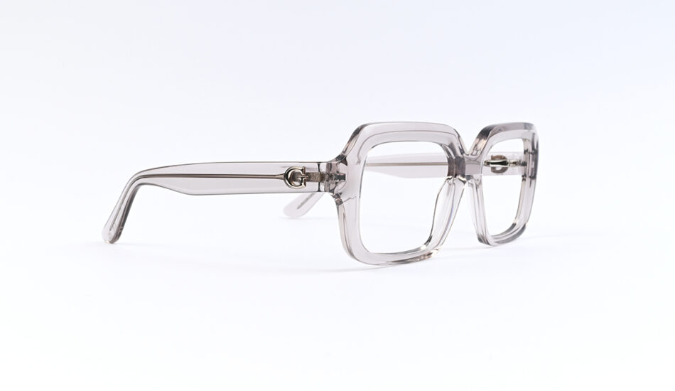 Clear translucent square-frame eyeglasses resting on a white surface.